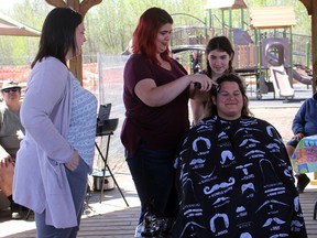 Erin Babcock’s daughter watches as Babcock has her head shaved this past weekend.