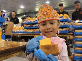 Four-year-old Madisyn Hess, Miss Six Nation's Tiny Tot, helps hand out bread and cheese on Monday at the Gaylord Powless Arena. 
Michelle Ruby/The Expositor