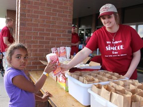 Volunteer Karissa Boylan hands a bag of popcorn to eight-year-old Oliveah Carter of Kitchener on Sunday evening at We Believe in Simcoe, a two-day festival held annually since 2010. A huge crowd enjoyed food, games and fireworks, all of it free, at Calvary Church. Michelle Ruby/Simcoe Reformer