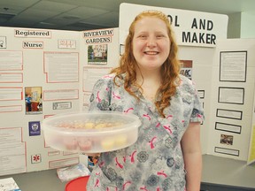 Alyssa Leach, a Grade 11 student at Ursuline College Chatham, holds up a tray of apple sauce in front of her presentation for her co-op placement at Riverview Gardens inside the school's cafeteria May 16. Tom Morrison/Chatham This Week