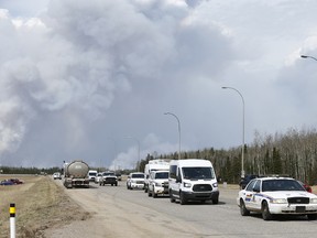 Police lead a convoy past the corner of Highways 63 and 881 on Wednesday, May 4, 2016, the day after a wildfire forced the evacuation of Fort McMurray, Alta. Ian Kucerak/Postmedia Network