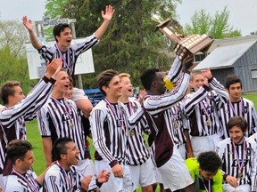 Holy Trinity Titans captain Kelvin Minja hoists the NSSAA boys soccer trophy while the rest of his team celebrates on Tuesday at Simcoe Composite School. The Titans beat the Sabres 2-1 in overtime to claim their second Norfolk title in the last three years.
JACOB ROBINSON/Simcoe Reformer