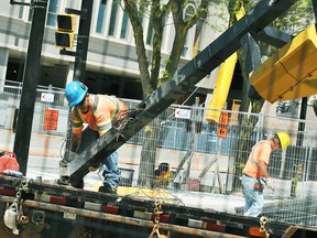 A construction worker helps move a street light pole attached to a crain to a trailer bed at a construction site at the corner of King Street West and Fifth Street in downtown Chatham May 23, 2018. A representative from the municipality has said the area will be fully accessible doing the RetroFest events this Friday and Saturday. (Tom Morrison/Postmedia Network)