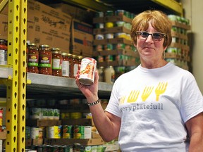 Brenda LeClair, executive director of Outreach for Hunger, holds up a canned good inside the food bank during its launch for the Every Plate Full campaign on May 29. LeClair said the goal of the campaign is to raise awareness about hunger in the community. (Tom Morrison/Postmedia Network)