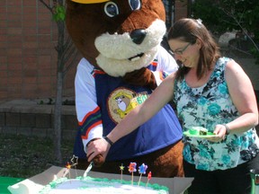 Danielle Gabruck (right) gave Bertie the Beaver a hand cutting the cake on the occasion of his 60th birthday, celebrated at the Fairview Provincial Building May 22.