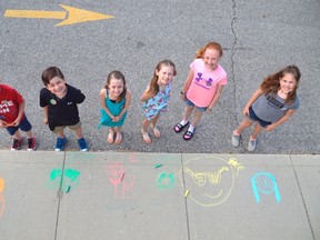 Students at Locke's Public School including, from left, Jacob Langley, Kayden Martin, Ella Dodge, Fiona Lavery, Ava Dodge, and Jennifer McDonald, take a break to colour the sidewalk near the building. On Saturday they, other kids, and community members will be at the public school to participate in 100 in 1 Day, a global initiative coming to St. Thomas for the first time this year. (Louis Pin/Times-Journal)