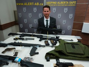 Mike Tucker, communications director for the Alberta Law Enforcement Response Team, with firearms, over-capacity magazines and body armour seized as the result of an ALERT investigation in Edmonton and Fort McMurray. Larry Wong/Postmedia Network