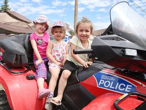 Ceara Levesconte, along with Meadow and Autumn Morin, enjoy sitting aboard an ATV, courtesy of the Greater Sudbury Police rural unit, at the grand opening of the Ryan Heights Accessible Playground in on Sunday. (Gino Donato/Sudbury Star)