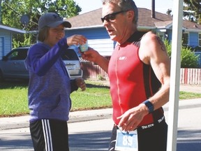 Tinman Triathlon volunteer Norah Gartly, 14, gives Kelly Eisler, from Calgary, a cup of water Saturday as he completes the running part
of the triathlon. Jasmine O'Halloran Vulcan Advocate