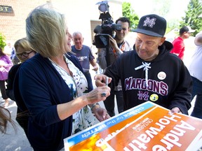 Longtime liberal supporter Randy Dewael of Chatham gets Andrea Horwath to autograph his election sign during a campaign stop in Chatham on Monday. Mike Hensen/Postmedia Network