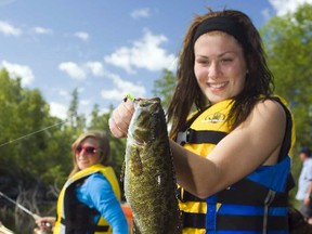 Islay Smedley hoists a nice smallmouth bass from the Turtle River, watched by her sister, Lillian. This photo was part of the package, entitled Tackling the Turtle, that won James Smedley second-place honours in the Outdoor Writers of Canada (OWC) National Communication awards. JAMES SMEDLEY/SPECIAL TO THE STAR