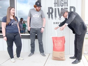 KASSIDY CHRISTENSEN HIGH RIVER TIMES/POSTMEDIA NETWORK. Photographed from left to right are Emily Gusse, High River Brewing Company sales and marketing manager and taproom manager, Kevin Guichon, owner and head brewer, and Mayor Craig Snodgrass who on May 18 ceremoniously opened a bag of malt for the grand opening of High River Brewing Company. The grand opening took place May 18, 19 and 20.