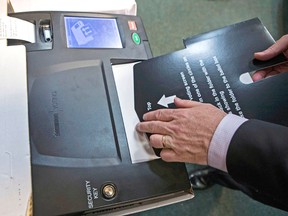 Ontario's Chief Electoral Officer Greg Essensa slides a ballot into a vote tabulator as he demonstrates an electronic voting machine.
THE CANADIAN PRESS/Chris Young