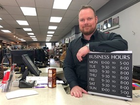Rob Russell, owner of MacLeods Scottish Shop and head of the BIA, holds a board showing his business' new business hours; starting June 12, his store will begin closing at 8 p.m. over the next several months. JONATHAN JUHA/THE BEACON HERALD/POSTMEDIA NETWORK