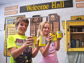 Emerson and Chloe, Grade 4 students at Gregory Drive Public School, hold up canned goods Monday next to the free little pantry they built with their class. The pantry will be stationed at the community gardens at Grand Avenue East and Victoria Avenue in Chatham starting June 23. Tom Morrison/Chatham This Week