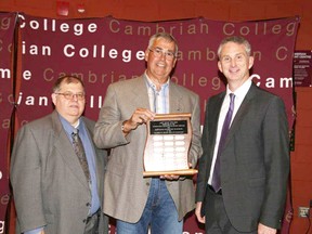 Glen Retty, left, chair of Cambrian College's board of governors, and Bill Best, right, president of Cambrian College, make a presentation to Richard Fedec at Cambrian College’s annual Rendezvous event held on June 7. Supplied photo