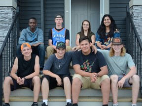 A group of 10th grade students sit on the steps of a home that they all had a part in building. The students were celebrating their years' work by giving tours of the two houses that they helped build in the Riverside community.