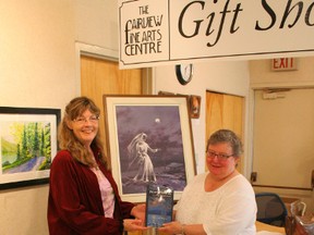 Elesa Diane Willies (left), of Grande Cache, author of Footsteps and Whispers, presented a copy of her book to Elaine Stenbraaten, president of the Fairview Fine Arts Society, for the permanent collection at the Fine Arts Centre. The painting behind them of the Grey Lady at Dunvegan, by Peace country artist Robert Guest, was featured on the cover of Willies' first book.