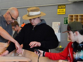 Teacher David Vine, left, assists students Quentin Bloemendal, middle, and Joe Le Blanc, right, during the Boats and Bikes class at Strathroy District Collegiate Institute. (Louis Pin/Postmedia News)