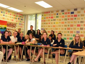 St. Michael Catholic Secondary School teacher Tim O’Connor (left) and his grade 12 world religions class sit in front of the teacher’s social justice wall, on which O’Connor has posted the names of peacemakers daily for nearly a decade. After placing two final names on the wall on Friday, O’Connor will have to take it down to allow for renovations to his classroom over the summer. Galen Simmons/The Beacon Herald/Postmedia Network