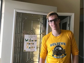 Xavier LaBelle returns home after spending several weeks in the hospital recovering from the April 6 bus crash that resulted in the deaths of 16 people. Behind him, a hand-written sign that reads “Welcome Humboldt Broncos Home Xavier.” In the photo, LaBelle sports a Humboldt Bronocs shirt and a large smile