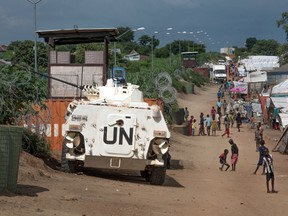 In this  photo taken Monday July. 25, 2016, Some of more than 30,000 Nuer civilians sheltering in a United Nations base in South Sudan's capital Juba for fear of targeted killings by government forces walk by an armored vehicle and a watchtower manned by Chinese peacekeepers. South Sudanese government soldiers raped dozens of ethnic Nuer women and girls last week just outside a United Nations camp where they had sought protection from renewed fighting, and at least two died from their injuries, witnesses and civilian leaders said. AP Photo/Jason Patinkin