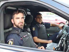 Constables Marc Savoie, left, and Ian Siraj sit in a police cruiser on Wednesday, June 15, 2018 in Stratford, Ont. (Terry Bridge/Stratford Beacon Herald)