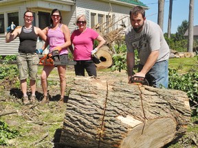 Sheena Yarek, left, of Old Highway 24 south of Waterford, was in a better mood Friday after a dozen friends and family came over to help clear debris from a tornado this week that toppled a dozen trees on her property. With Yarek, from left, are Stacy Bruce of Wilsonville and Penny Yarek of Scotland. Taking on the big trunk at right is Brandon Marsh of Burford. MONTE SONNENBERG / SIMCOE REFORMER