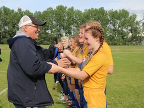 Hal Souster, left, recently handed out gold medals to the Bev Facey girls rugby team as one of his final duties as athletic director for the school, a position he has held for the last 25 years. Photo Supplied