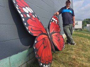 Artist Ania Nunns shows off a butterfly created by Woodstock students that will become part of a giant mural over the coming weeks on the side of the Midas Muffler building. (HEATHER RIVERS/SENTINEL-REVIEW)