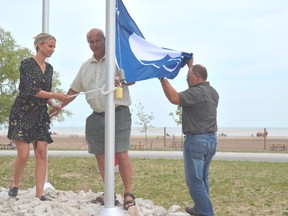 Mayor of Bayham Paul Ens, centre, helps raise the blue flag in Port Burwell, awarded by Environment Defence for the municipality's dedication to safe environmental practices on the shoreline. Helping him was Tessa Soltendieck, left, program coordinator with Environment Defence, and Ed Roloson, with the municipality. (Louis Pin/Times-Journal)