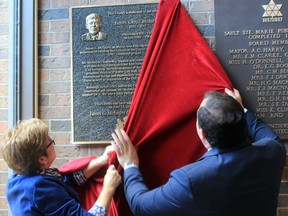 Sault Ste. Marie Public Library chair Toni Nanne-Little and Mayor Christian Provenzano unveil a new plaque dedicated to former mayor James McIntyre on Monday afternoon at the Centennial library branch.