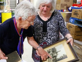 Luke Hendry/The Intelligencer
Lois Foster of Belleville points out a relative in a 1909 photo of her husband's family as Susanne Quinlan listens Monday at Gleaners Food Bank in Belleville. The photo was found among items donated for the food bank's July yard sale. Foster learned of its discovery after Quinlan contacted The Intelligencer in an attempt to find descendants of those in the picture.