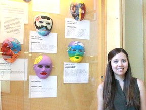 Jessica West of the Seizure and Brain Injury Centre sets up a masks exhibit at the Timmins Public Library on Tuesday. The masks will be on display until the end of the month as part of Brain Injury Awareness Month.