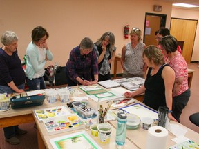 Marjorie Henn (centre, in checked shirt) shows painters how to add details to a watercolour painting that give depth and make it look more realistic.