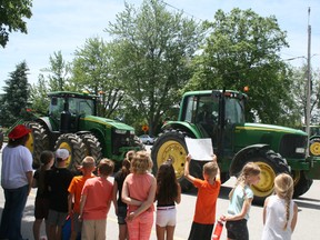 Tractors parade around St. Patrick Catholic School during the Tractor Day festivities. (William Proulx/Exeter Lakeshore Times-Advance)