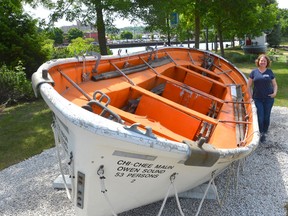 Community Waterfront Heritage Centre curator Wendy Tomlinson stands with one of two original lifeboats off the Chi-Cheemaun that is now installed at their site. (Rob Gowan The Sun Times)