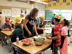 Anne Munier, Loving Spoonful's GROW Project co-ordinator, helps students chop strawberries and spinach. Centennial Public School students and volunteers harvested their garden on Monday. Students and volunteers prepared a salad bar with their homegrown produce.  (Sebastian Bron/The Whig-Standard)