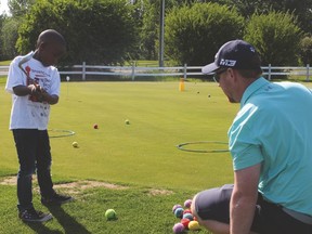 Dave Henzie, head golf pro at the Nanton Golf Club, helps Siya Mbambo learn how to chip onto the green June 7 during the junior golf program at the golf club. Ian Gustafson Nanton News