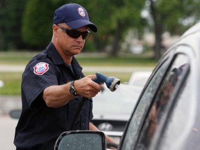 Firefighter John McNutt pitches in Saturday during hospice car wash fundraiser at North Bay Toyota.