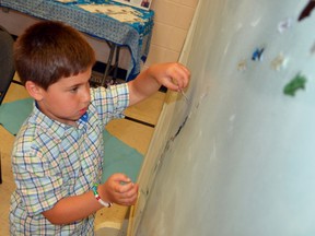 Layth Hassan, 5, attaches a tiny paper fish onto a mural at Saturday's Celebrating Multiculturalism Through Arts event in downtown Owen Sound. DENIS LANGLOIS/THE SUN TIMES