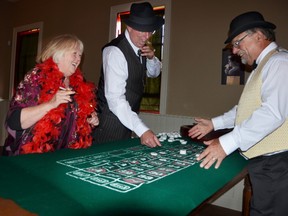 Heritage interpreter Don Sankey, right, waits as Susan Martin and Ted Noble place their bets inside The Black Rabbit, a "speakeasy" at Grey Roots' Saints and Sinners event. DENIS LANGLOIS/THE SUN TIMES