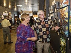 Linda Campbell of the Capitol Arts Market in Simcoe listens as artist George Conklin of Walsingham describes his impressionistic works depicting scenes in the Canadian Shield on Sunday during the Small Works Art Show and Sale. Brian Thompson/The Expositor