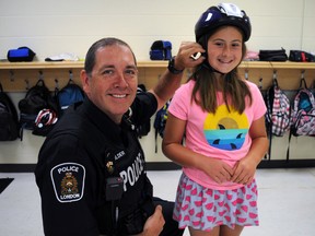 Emma Coleman, 10, a Grade 4 student from St. Thomas More Catholic elementary schools, gets a hand with her new bike helmet from school safety officer Const. Chris Golder. Helmets on Kids has kicked off their annual awareness campaign while distributing hundreds of helmets to youth in London and Middlesex County, just in time for the summer.