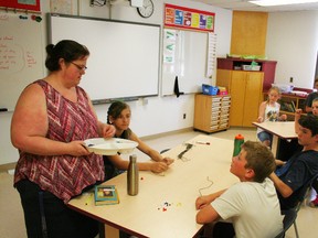EE Oliver teacher Jennifer Daniel hands out coloured beads and strings while explaining the principles behind the First Nations' medicine wheel, as taught to her by an Elder. The students used the beads to make their own medicine wheel. The activities were part of the school's National Indigenous Peoples Day celebrations.