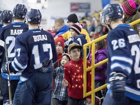 Kids line up to high five the Eagles hockey players, including a boy with lights on his sweater, during the Canmore Eagles AJHL game against the Calgary Mustangs on Family Day at the Canmore Recreation Centre on February 19, 2018. Pam Doyle/www.pamdoylephoto.com.