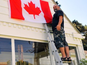 Residents in Port Dover have been busy this week preparing their homes for the town's Canada Day celebrations to take place Sunday. One of those people is Larry Mitchell, who was hanging flags at his St. George St. property Friday morning. JACOB ROBINSON/Simcoe Reformer