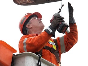 Utilities worker installs LED streetlights.