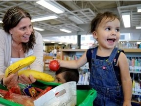 Lisa Skirten, an office administrator with Investing in Children, shares a snack with Issabella, 2, and her older brother Isaiah, 3, who were visiting the Jalna library branch with their grandmother, Mandy Williams. Skirten dropped off a box of healthy snacks at the neighbourhood library, one of seven locations taking part in a new pilot project aimed at getting nutritious food into the bellies of London kids. CHRIS MONTANINILONDONER