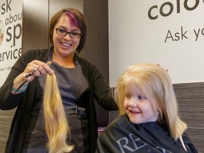 Tia Beauchamp, left, shows four-year-old Brooklyn Todd her freshly shorn hair for the charity Locks of Love at Chatters in Airdrie on Thursday, June 28, 2018. Todd donated 12 inches of her hair to the non-profit that provides hairpieces for sick kids